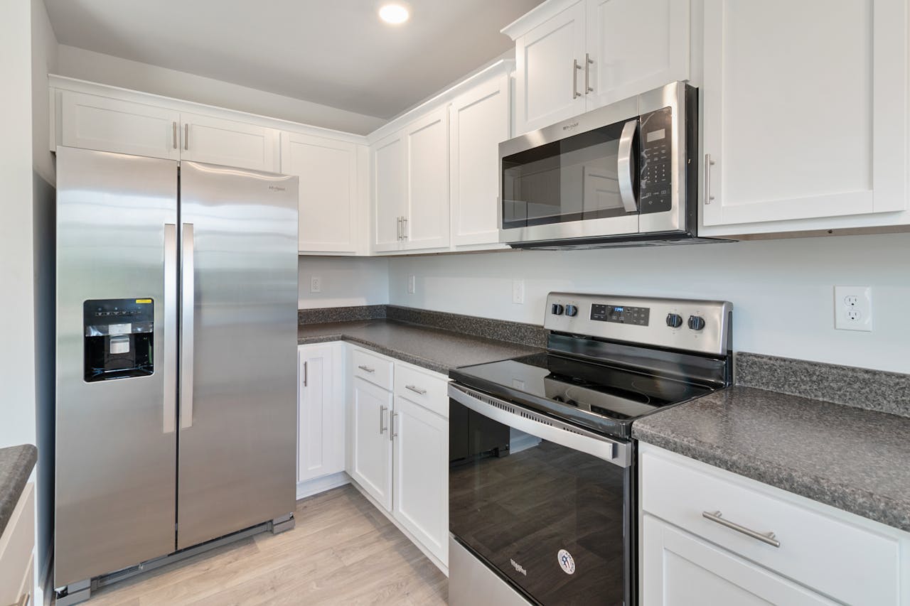 about-02 Sleek kitchen with stainless steel appliances and white cabinetry.